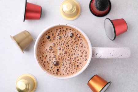 Cup of coffee and capsules on light table, flat layの写真素材