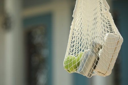 Conscious consumption. Net bag with eco friendly products outdoors, closeup. Space for textの写真素材