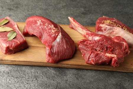 Pieces of raw beef meat and spices on gray textured tableの写真素材