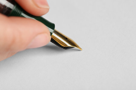 Woman with fountain pen above white paper, closeup. Space for textの写真素材