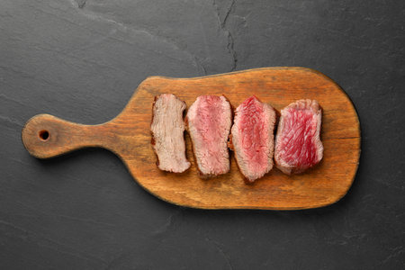 Delicious sliced beef tenderloin with different degrees of doneness on black table, top viewの写真素材