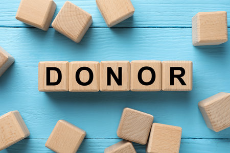 Cubes with word Donor on light blue wooden table, flat layの写真素材