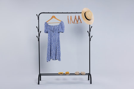 Rack with accessories and stylish women`s dress on wooden hanger against light gray backgroundの写真素材