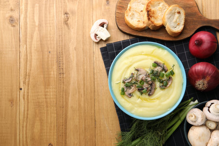 Bowl of tasty cream soup with mushrooms, green onions and dill on wooden table, flat lay. Space for textの写真素材
