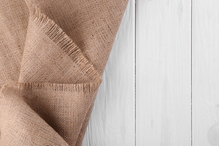Brown burlap fabric on white wooden table, top view. Space for textの写真素材