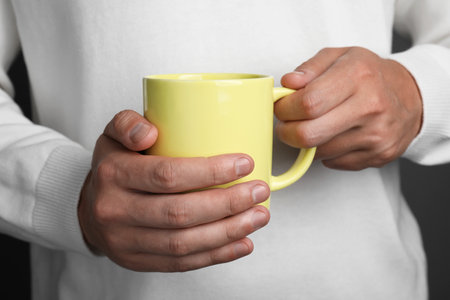 Man holding yellow mug on gray background, closeupの写真素材