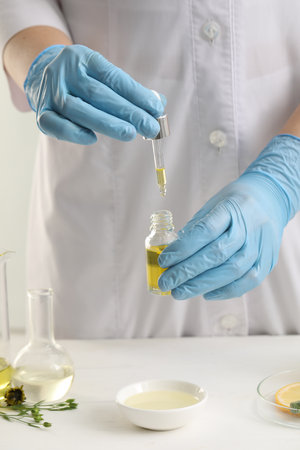 Scientist developing cosmetic oil at white table, closeupの写真素材