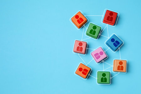 Teamwork. Wooden cubes with human icons linked together symbolizing cooperation on light blue...
