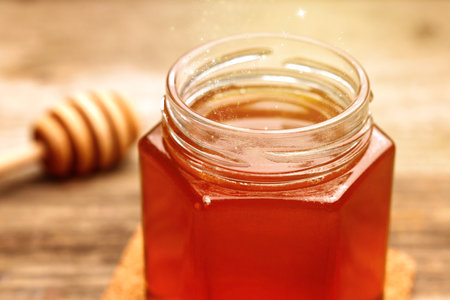 Natural honey in glass jar under sunlight, closeupの写真素材
