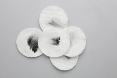 Dirty cotton pads after removing makeup on light gray background, flat lay