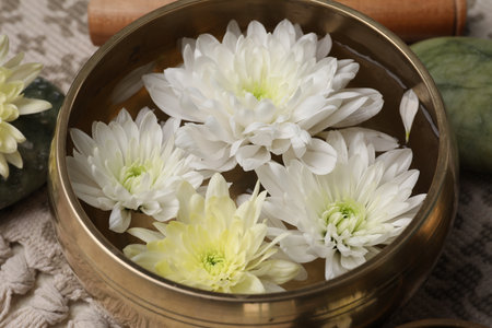 Tibetan singing bowl with water and beautiful chrysanthemum flowers on table, closeupの写真素材