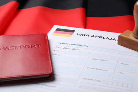 Immigration to Germany. Visa application form, passport and stamp on flag, closeupの写真素材