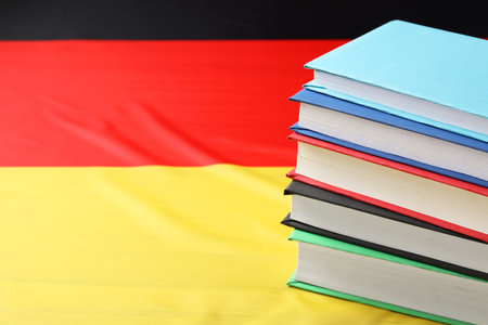 Learning foreign language. Different books on flag of Germany, space for textの写真素材