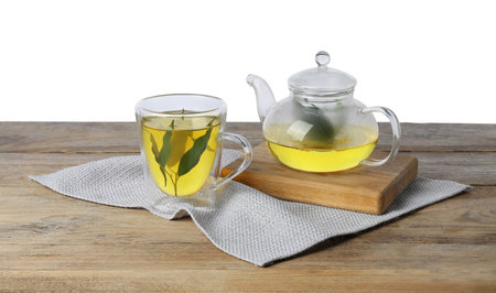 Refreshing green tea in cup and teapot on wooden table against white backgroundの写真素材