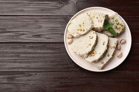 Pieces of tasty halva with pistachios and mint on wooden table, top view. Space for textの写真素材