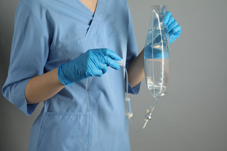 Nurse with IV infusion set on gray background, closeupの写真素材