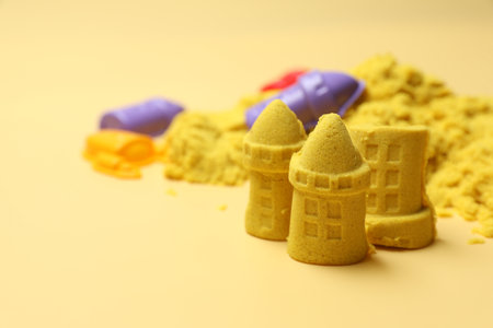 Castle figures made of yellow kinetic sand on beige background, closeup. Space for textの写真素材