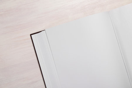 One open photo album on wooden table, top view