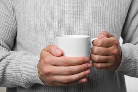 Man holding white mug on light gray background, closeupの写真素材