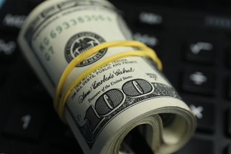 Money exchange. Rolled dollar banknotes on calculator, closeupの写真素材