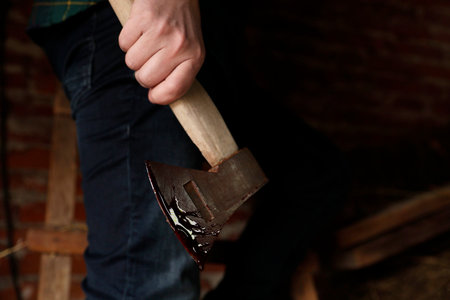 Man holding bloody ax indoors, closeup viewの写真素材