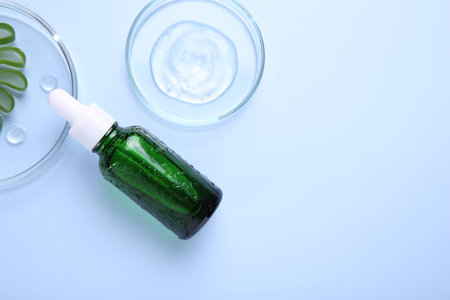 Cut aloe vera, bottle and cosmetic gel on light blue background, flat lay. Space for textの写真素材