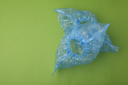 Pair of blue medical shoe covers on green background, top view. Space for textの写真素材