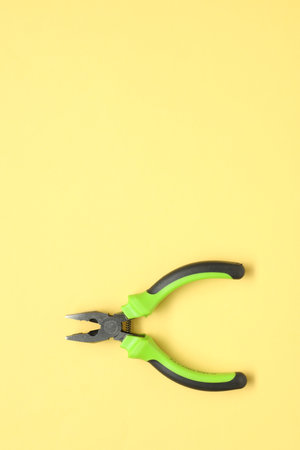 Combination pliers on yellow background, top view. Space for textの写真素材