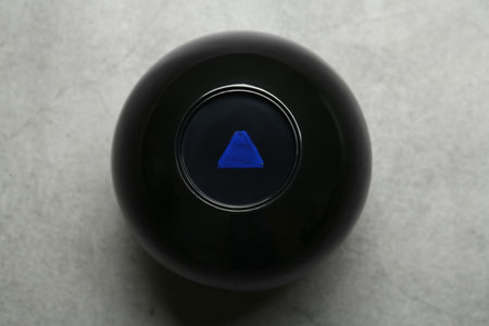 Magic eight ball on gray table, top view