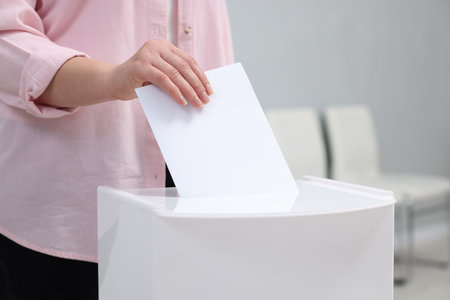 Woman putting her vote into ballot box on blurred background, closeupの写真素材