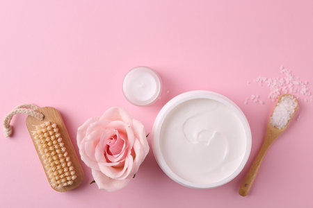Jars of cream, sea salt and rose flower on pink background, flat lay with space for text. Body care productsの写真素材