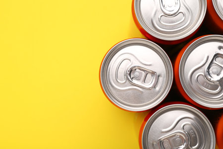 Energy drink in cans on yellow background, top view. Space for textの写真素材