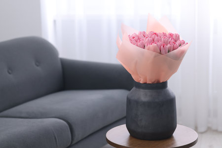 Bouquet of beautiful pink tulips in vase on wooden table indoors, space for textの写真素材