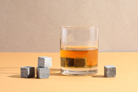 Whiskey stones and drink in glass on orange table, closeupの写真素材