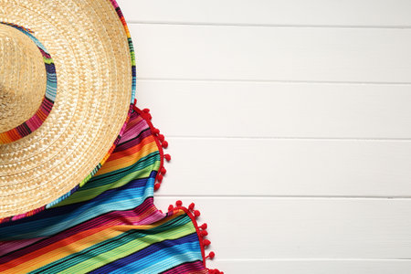Mexican sombrero hat and colorful poncho on white wooden background, flat lay. Space for textの写真素材