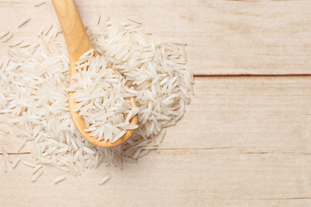 Raw basmati rice and spoon on white wooden table, top view. Space for textの写真素材