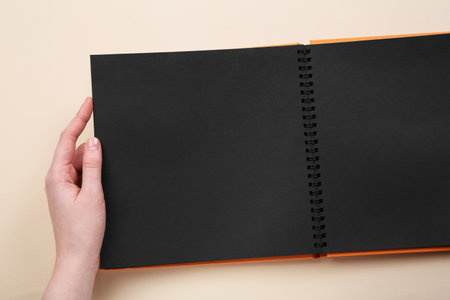 Woman with open photo album at beige background, top view. Space for textの写真素材