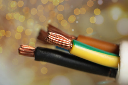 Colorful electrical wires against golden background with blurred lights, closeup. Bokeh effect