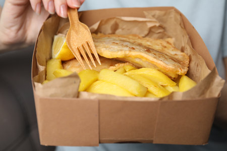 Woman eating delicious fish and chips on gray background, closeupの写真素材