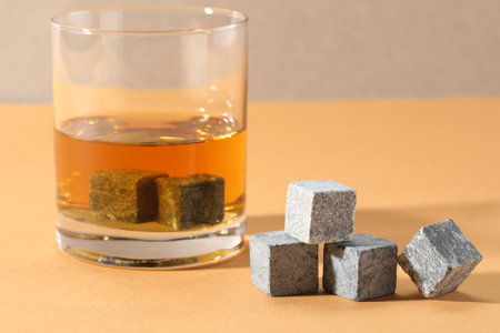 Whiskey stones and drink in glass on orange table, closeupの写真素材