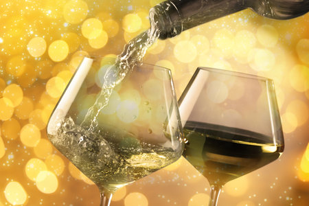 Pouring white wine into glass against background with blurred lights, closeup. Bokeh effectの写真素材