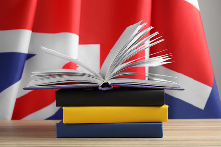Learning foreign language. Different books on wooden table near flag of United Kingdomの写真素材