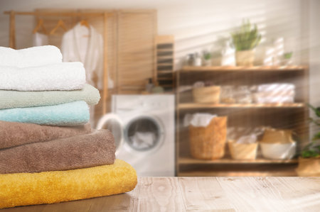 Folded clean towels on wooden table in laundry room, space for textの写真素材