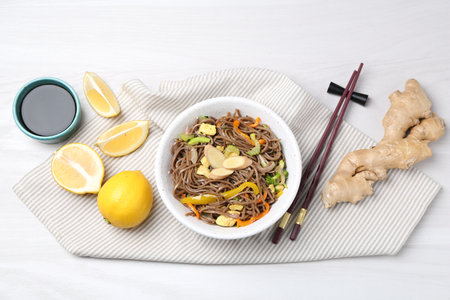 Stir-fry. Delicious cooked noodles with chicken and vegetables in bowl served on light wooden table, flat layの写真素材