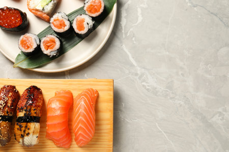 Delicious sushi rolls on light gray marble table, flat lay. Space for textの写真素材