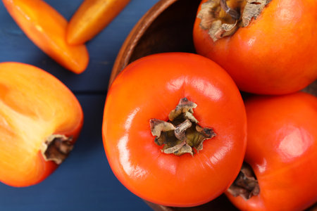 Delicious ripe persimmons on blue table, top viewの写真素材