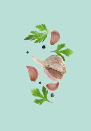 Fresh garlic, peppercorns and parsley falling on light blue backgroundの写真素材