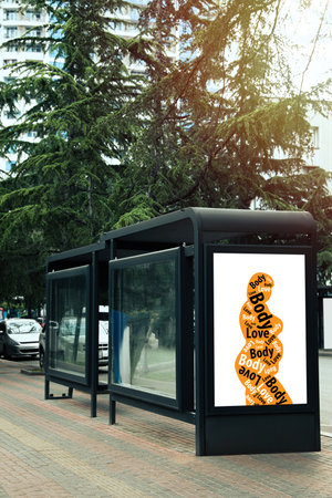 Signboard with orange silhouette of plus-size model with words Body Love on city streetの写真素材
