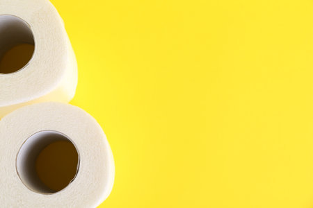 Soft toilet paper rolls on yellow background, top view. Space for textの写真素材