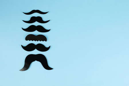 Fake paper mustaches on light blue background, flat lay. Space for textの写真素材